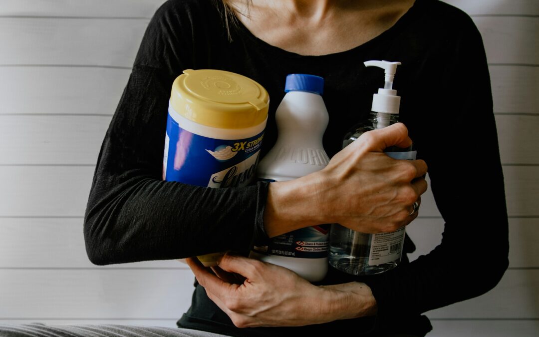 Person holding cleaning products in arms.